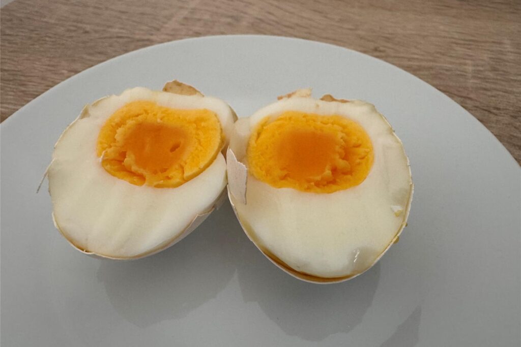 Ein in zwei Hälften geteiltes, hartgekochtes Ei, das im Airfryer gegart wurde.