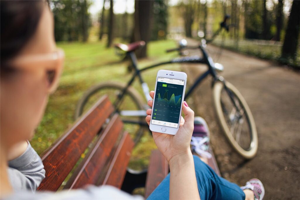 Eine Frau hält ein Handy vor ihr abgestelltes Fahrrad.