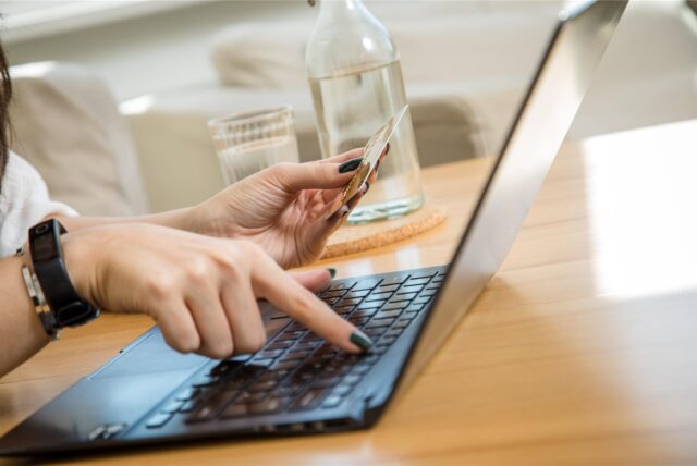 Eine Person gibt die Nummer einer Kreditkarte am Laptop ein. (Symbolbild)