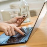 Eine Person gibt die Nummer einer Kreditkarte am Laptop ein. (Symbolbild)