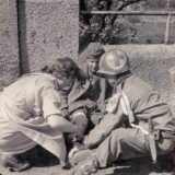 Eine deutsche Hilfsschwester assistiert einem Sanitäter der 8. Panzerdivision bei der Behandlung eines verwundeten jungen deutschen Soldaten. Das Foto soll bei der Schlacht um Unna am 11. April 1945 entstanden sein.