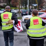Zwei Männer mit Verdi-Westen und eingerollten Gewerkschaftsfahnen.
