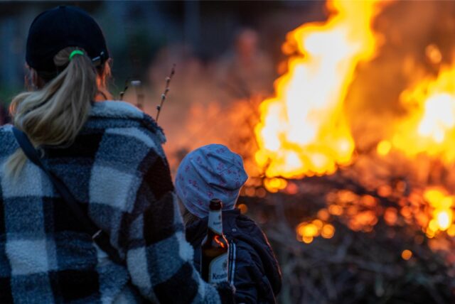 Eine Frau steht mit einem Kind vor einem Osterfeuer in Lünen.
