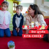Erzieherin Iris Chatzopoulos kniet in der Kita des Evangelischen Familienzentrums Aplerbecker Mark in Dortmund neben drei Kindern.