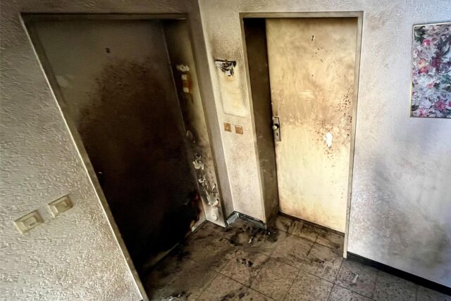 Das Foto zeigt zwei stark beschädigte Wohnungstüren in der ersten Etage des betroffenen Mehrfamilienhauses. Die linke Tür war in Brand geraten.