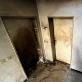 Das Foto zeigt zwei stark beschädigte Wohnungstüren in der ersten Etage des betroffenen Mehrfamilienhauses. Die linke Tür war in Brand geraten.