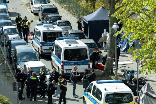 Polizisten und Beamte der Spurensicherung in weißen Schutzanzügen stehen am Fundort. Wegen einer männlichen Leiche wurde die Polizei am Morgen alarmiert. Die Umstände deuten auf eine Gewalttat hin.