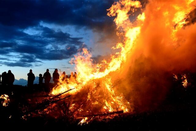 Zuschauer stehen bei einem traditionellen Osterfeuer.