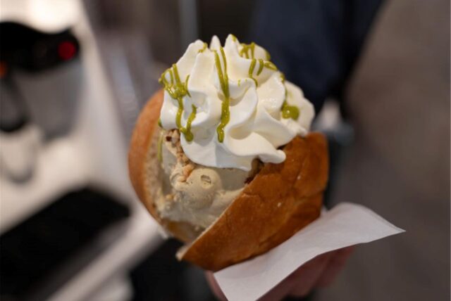 In einem Brioche-Brötchen befinden sich zwei Kugeln Eis mit Sahne oben drauf.