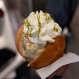 In einem Brioche-Brötchen befinden sich zwei Kugeln Eis mit Sahne oben drauf.