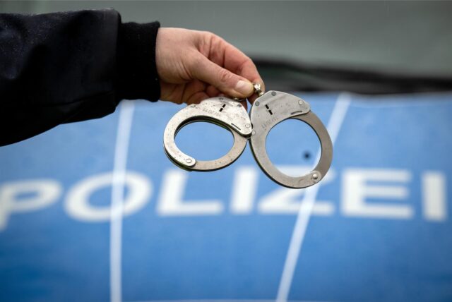 Ein Polizist hält ein Paar Handschellen.