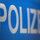 Weißer Schriftzug „Polizei“ auf blauem Hintergrund.