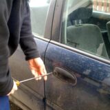 Ein Mann (Symbolbild) macht sich an einer Autotür zu schaffen.