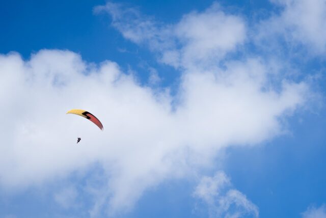 Ein Paraglider gleitet bei teilweise blauem Himmel durch die Luft.