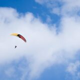 Ein Paraglider gleitet bei teilweise blauem Himmel durch die Luft.