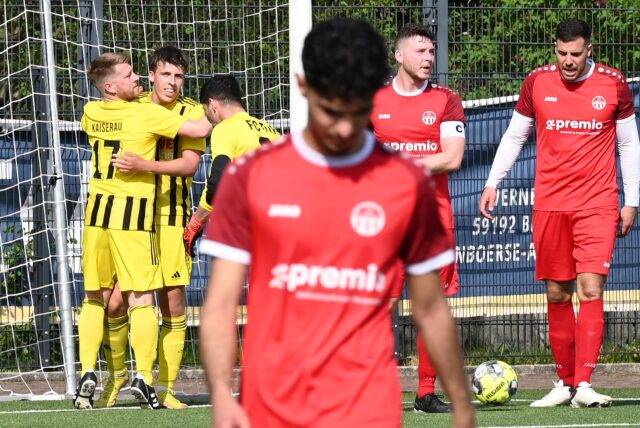 Nico Stender erhöht auf 4:0 für den SuS Kaiserau II und lässt sich von seinen Teamkollegen feiern, während die Bergkamener die Köpfe hängen lassen.