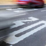 Auf dem Bild ist ein Autofahrzeug zu sehen, das sich auf einer Straße mit einer Geschwindigkeitsbegrenzung von 30 km/h bewegt. Die weiße Markierung auf der Fahrbahn signalisiert die Geschwindigkeitsbegrenzung.