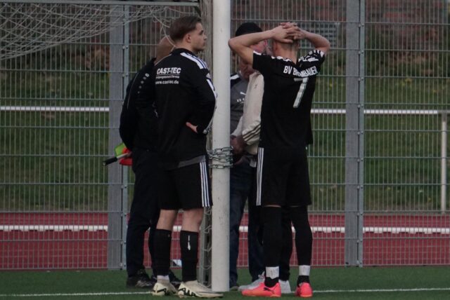 Spieler und Funktionäre des BV Brambauer stehen um einen Torpfosten und einer verschlossenen Kette.