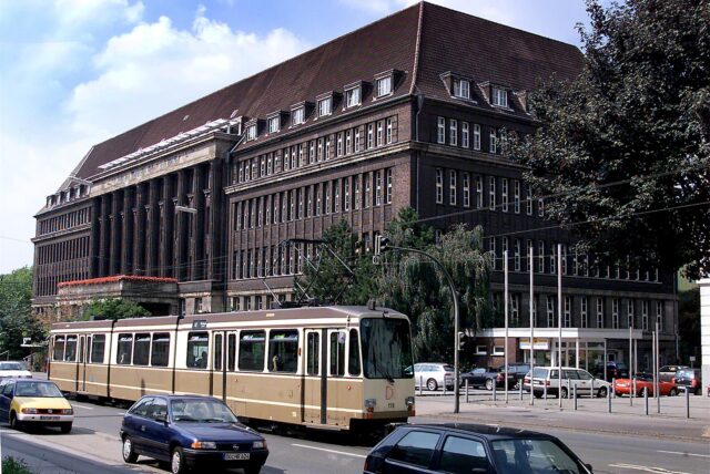 Ein altes Foto des ehemaligen Versorgungsamts in Dortmund, im Vordergrund Autos und eine Straßenbahn