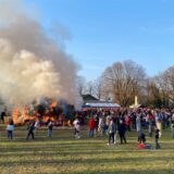 Menschen stehen in Overberge um das Osterfeuer herum.