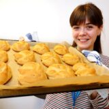 Reporterin Janka Hardenacke hält ein Backblech in den Händen, auf dem Brötchen in Hasenform liegen.