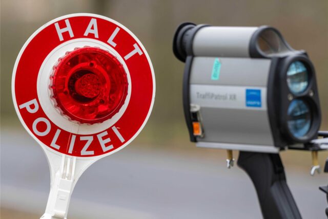 Ein Polizist hält eine Kelle zum Anhalten von Autos und ein Geschwindigkeitsmessgerät.