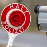 Ein Polizist hält eine Kelle zum Anhalten von Autos und ein Geschwindigkeitsmessgerät.