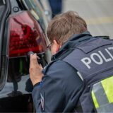 Ein Polizist kontrolliert die Scheinwerfer eines Autos.