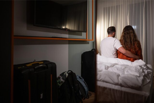 Zwei Menschen sitzen auf einem Bett im Hotelzimmer.