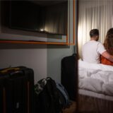 Zwei Menschen sitzen auf einem Bett im Hotelzimmer.
