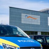 Ein Polizeiwagen steht vor einem Schwimmbad.