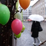 Regennasser Osterschmuck hängt am Stand eines Marktes.