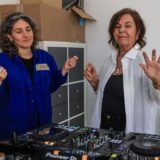Ingrid Jatho (r), DJ-Schülerin, tanzt beim DJ-Workshop für das Ü70-Publikum mit ihrer Dozentin Anna Cainelli (l) am Mischpult.