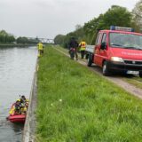 Ein Ruderboot der Feuerwehr ist im Wasser des Dortmund-Ems-Kanals. Auf dem Weg daneben steht ein Einsatzfahrzeug.
