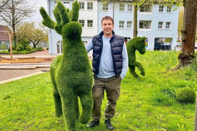 Yevhen Somin mit einem Rentier und einem Pferd im Kunstrasen-Look.