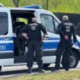 Polizeibeamte stehen vor einem Einsatzwagen.