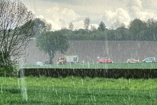 Feuerwehren stehen an der Töddinghauser Straße in Bergkamen. Feuerwehrleute löschen die Reste eines Osterfeuers.