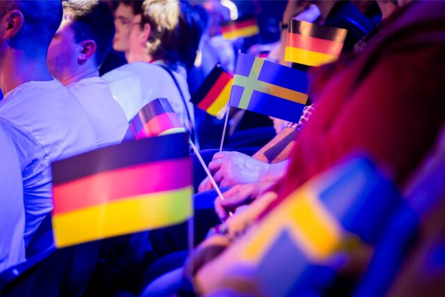 Zuschauer halten vor Beginn des Eurovision Song Contest die Fähnchen von Deutschland und Schweden in den Händen.