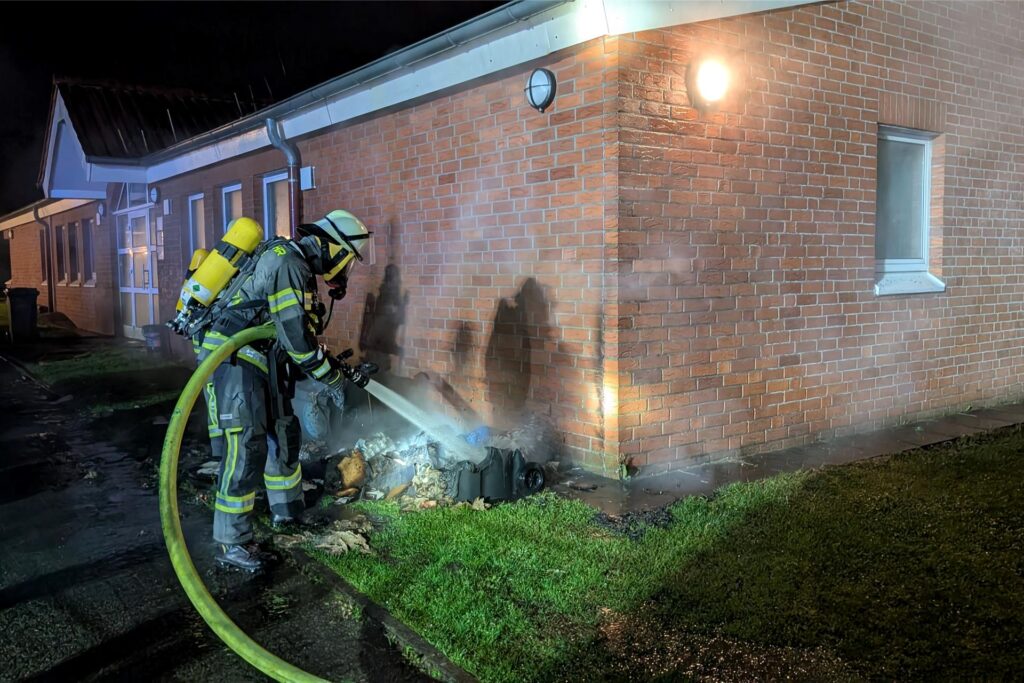 Ein Feuerwehrmann löscht das Feuer am Sportzentrum in Werne.