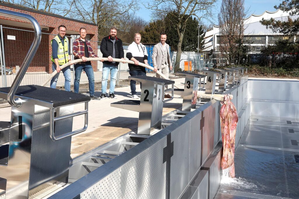 Mehrere Leute befüllen ein leeres Schwimmbecken im Kamener Sesekebad mit Wasser.