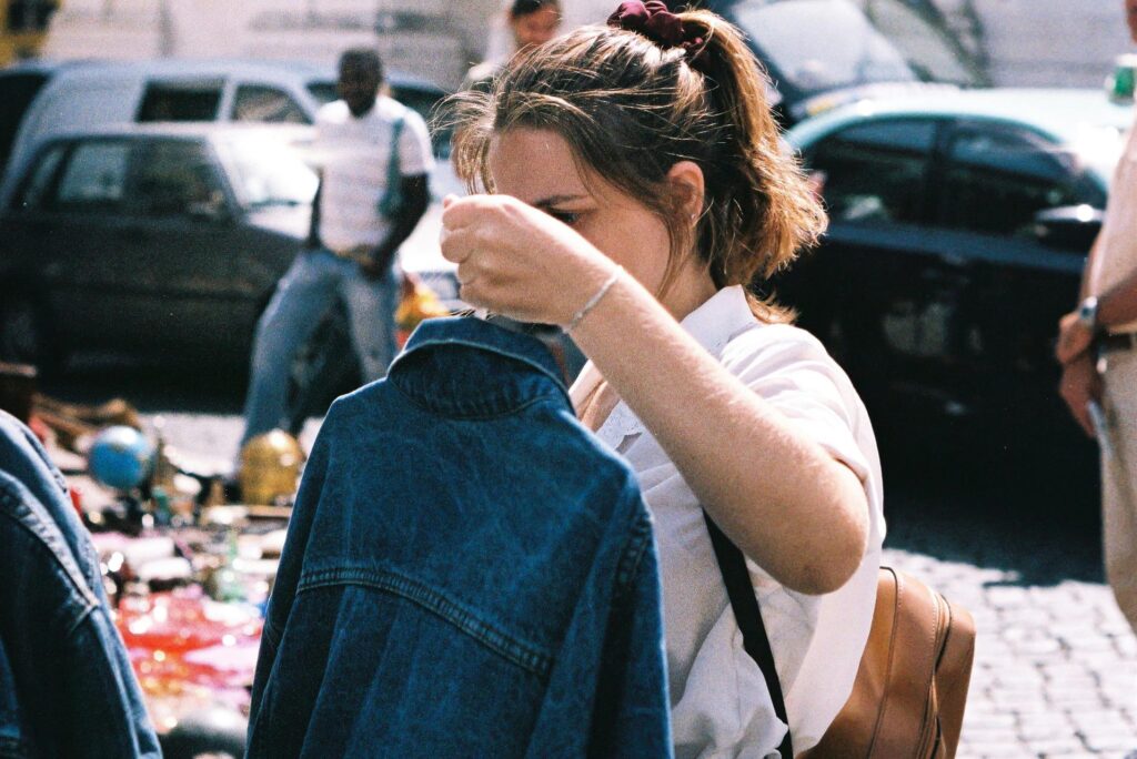Eine Frau hält auf einem Trödelmarkt in NRW eine Jeansjacke in der Hand.