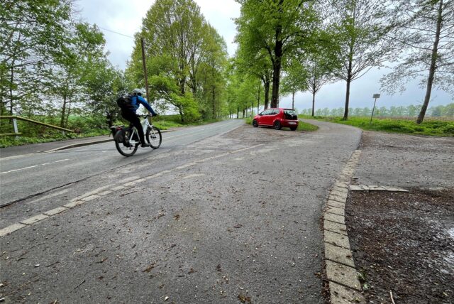 Ein Auto parkt an der Holzwickeder Straße während ein Radfahrer passiert.