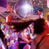 Feiernde Menschen unter einer schillernden Discokugel.