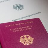 Eine Einbürgerungsurkunde der Bundesrepublik Deutschland und ein deutscher Reisepass liegen auf einem Tisch.