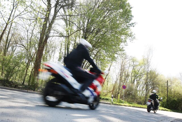 Zwei Motorradfahrer fahren über eine Landstraße.
