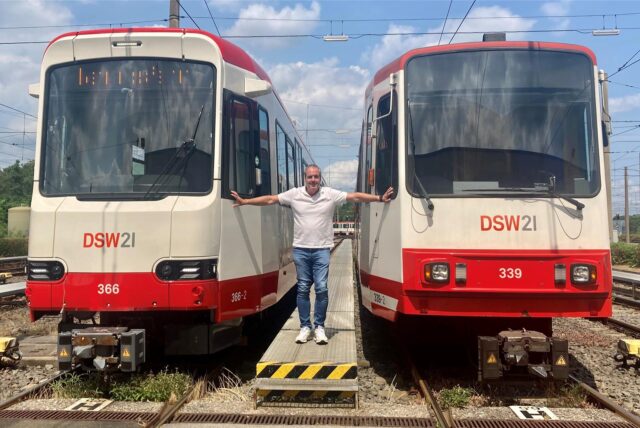 DSW-Betriebsleiter Ralf Habbes steht zwischen einer neuen Stadtbahn von HeiterBlick und einem alten B-Wagen, der noch umgebaut werden soll
