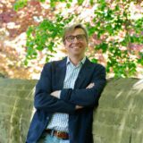 Michael Sacher lehnt an der Nachbildung der Unnaer Stadtmauer. Der Buchhändler und ehemalige Bundestagsabgeordnete tritt für die Bündnisgrünen in seiner Stadt als Bürgermeisterkandidat an.