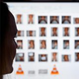 Symbolbild: Ein Ermittler sitzt vor einem PC, auf dem verpixelte pornografische Dateien abgebildet sind