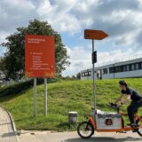 Ein Radfahrer fährt an einem Schild der FH auf dem Campus Nord vorbei.