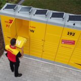 Ein DHL-Mitarbeiter legt ein Paket in eine Packstation.